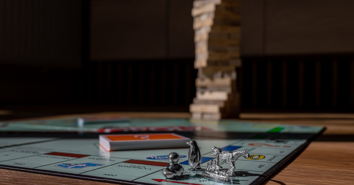 Close-up view of Monopoly board game with metal tokens and stacked Jenga blocks on a table.
